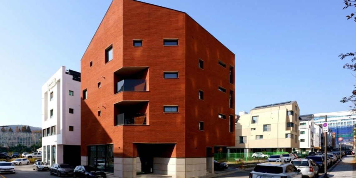 The crimson brick facade wraps the Cornerstone of LKSA housing unit in Korea